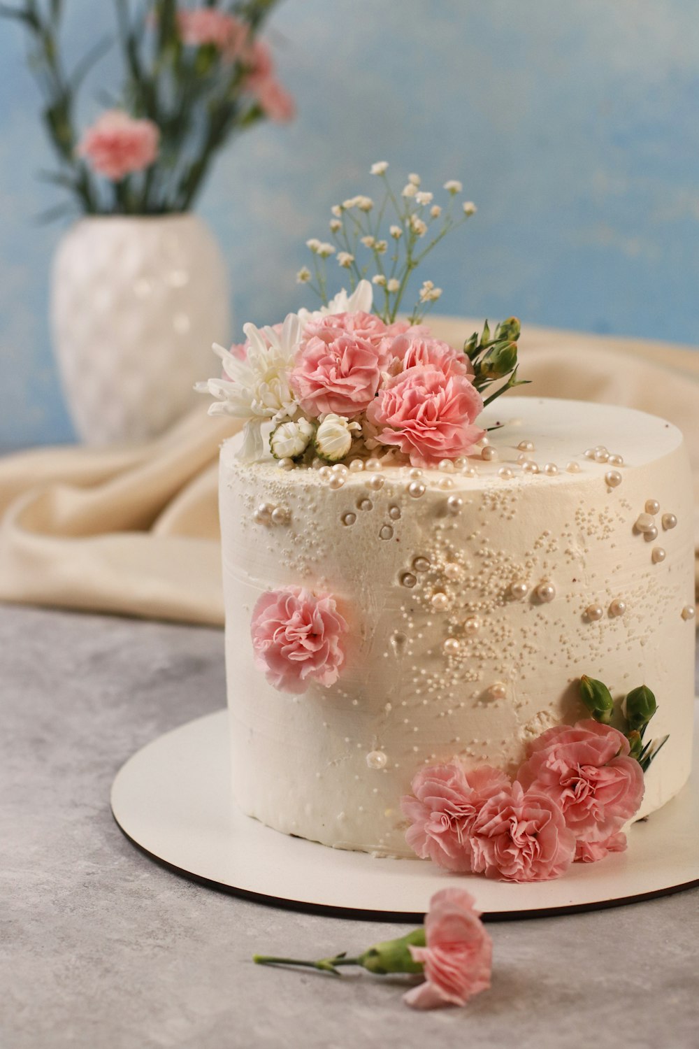 um bolo branco com flores cor-de-rosa em cima dele