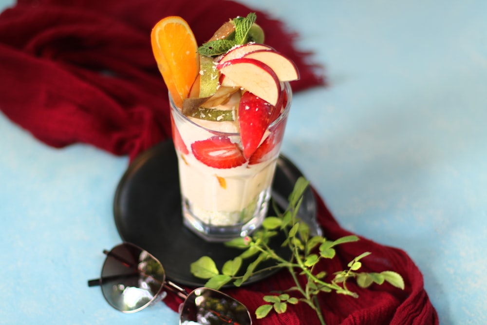 a glass of fruit and ice cream on a plate