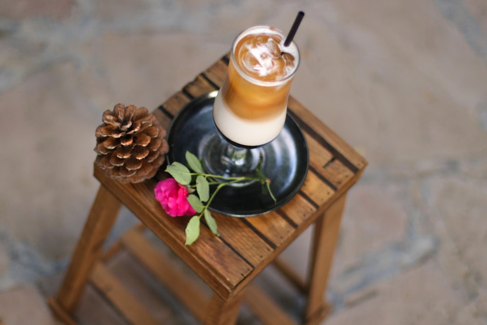 a drink on a table with a flower and a pine cone
