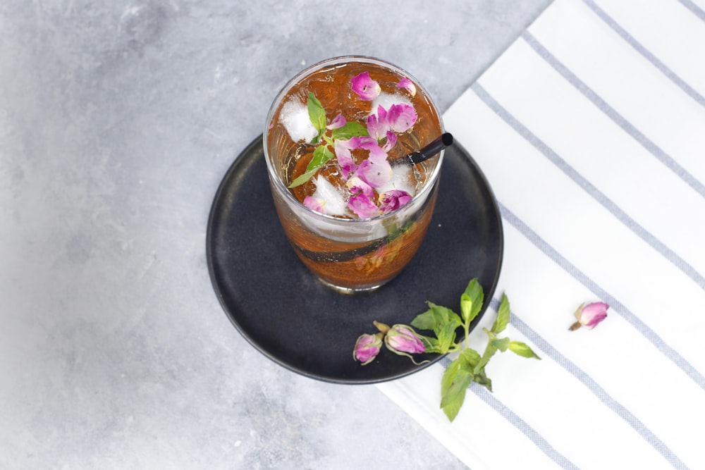 a black plate topped with a drink on top of a table