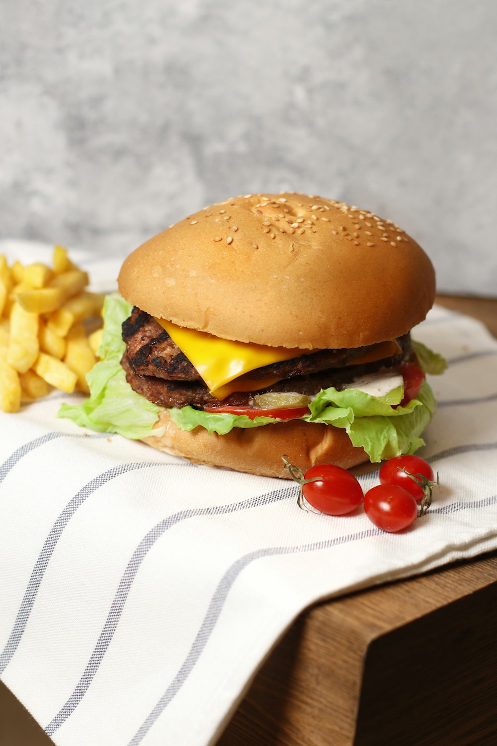 a hamburger with cheese and lettuce next to a pile of fries