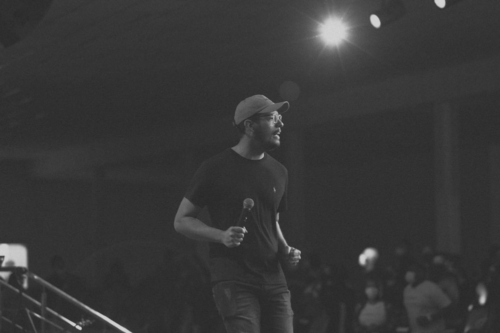 man in black crew neck t-shirt and black pants standing on stage