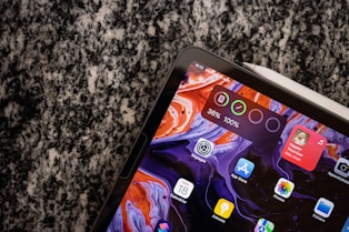 Close-up of a hand selecting digital files on a tablet with colorful icons representing different products.