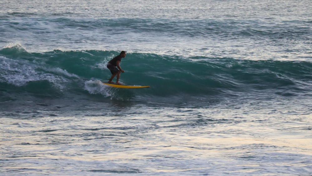 man in black wet suit surfing on sea waves during daytime