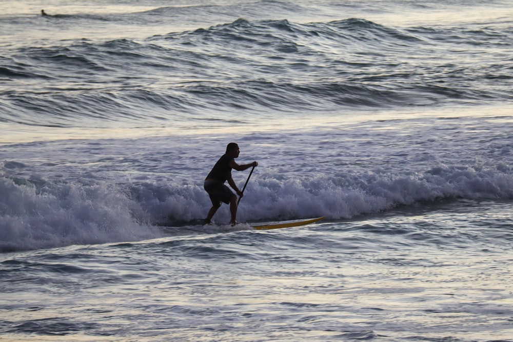 man in black wet suit surfing on sea waves during daytime