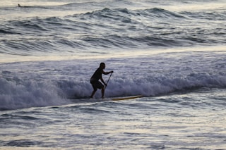 man in black wet suit surfing on sea waves during daytime