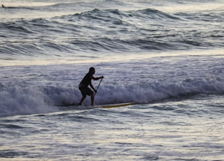 man in black wet suit surfing on sea waves during daytime