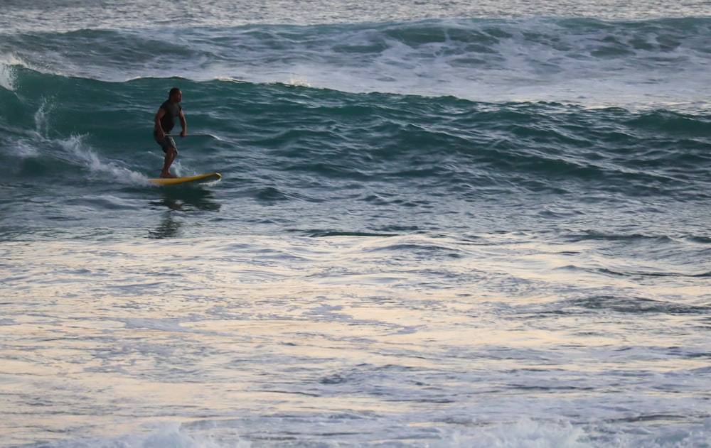 man in black wet suit surfing on sea waves during daytime