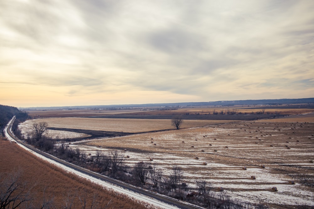 brown field under white clouds during daytime