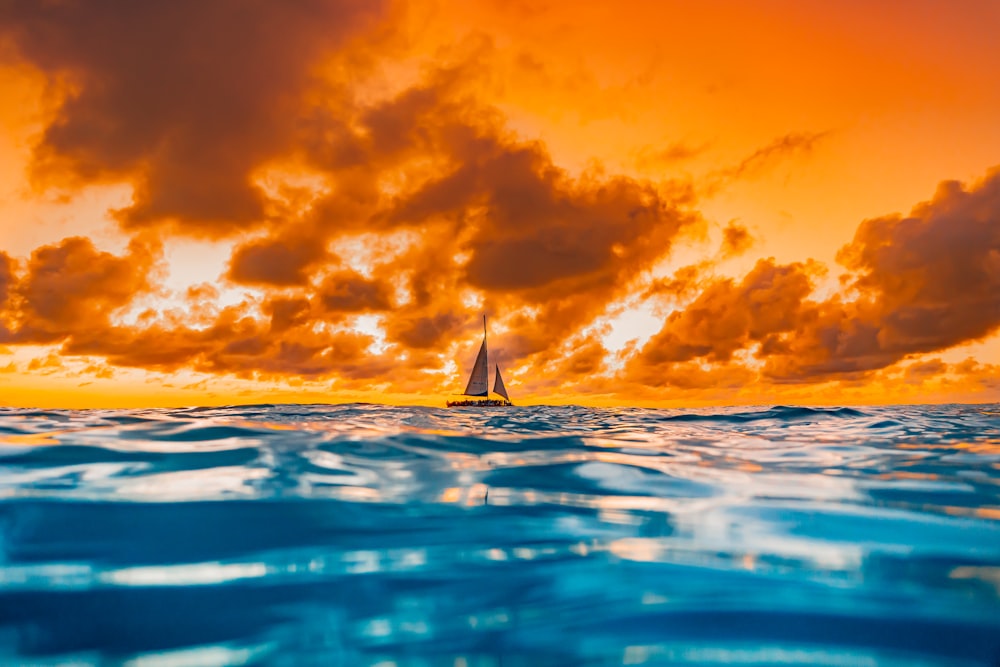 sailboat on sea under blue sky and white clouds during daytime