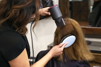 woman holding white and black hair blower