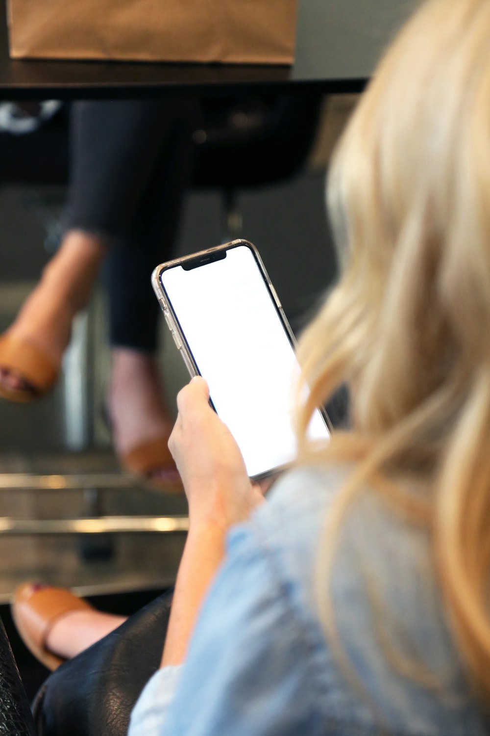 woman in blue shirt holding white smartphone