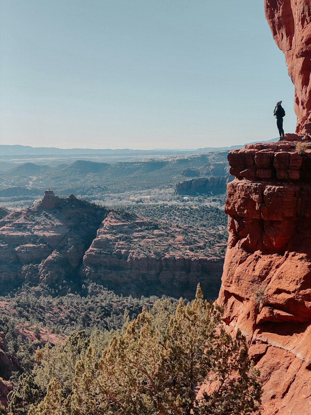 man sitting on brown rock formation during daytime