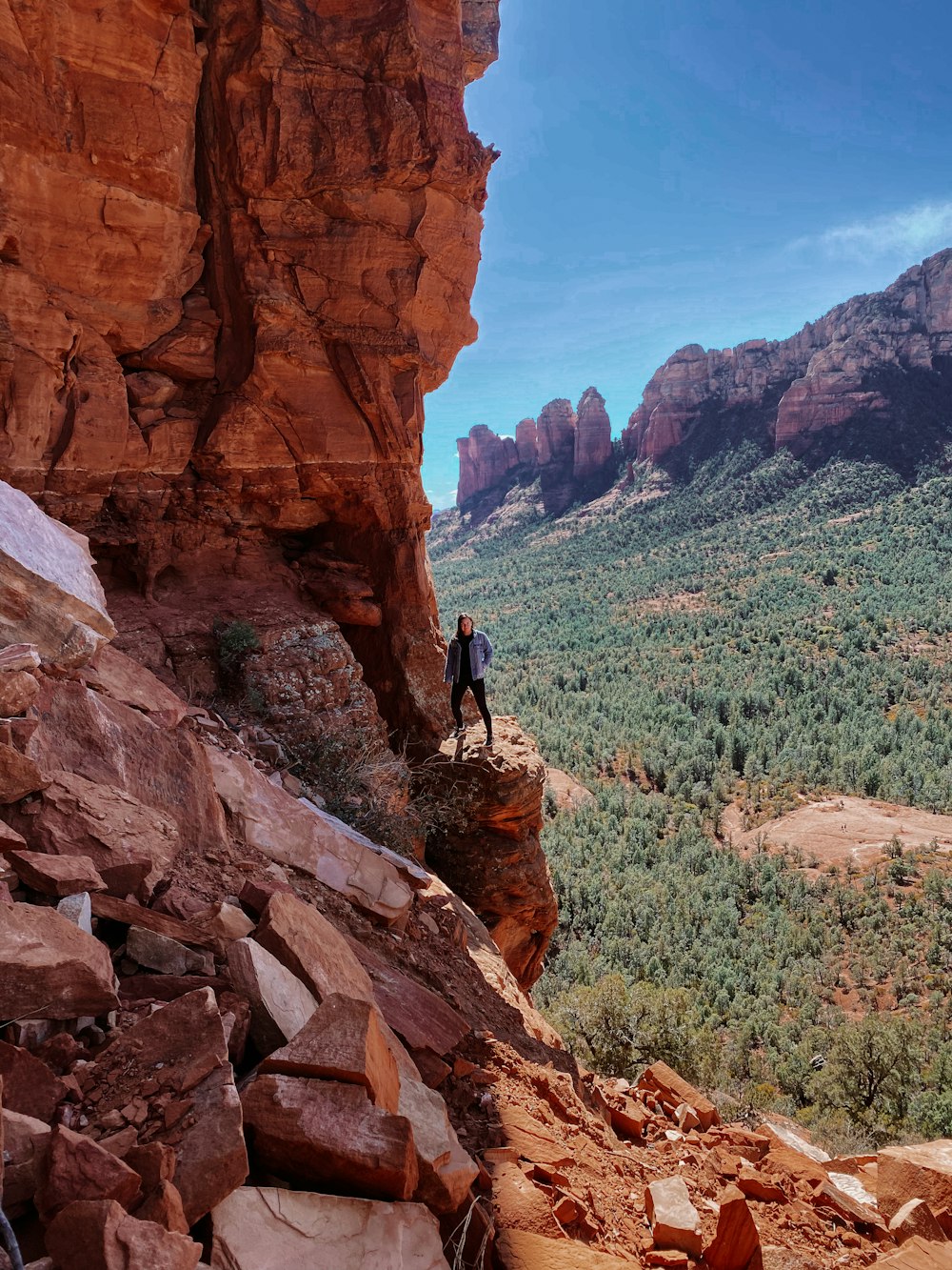 man in black jacket and brown pants standing on brown rock formation during daytime