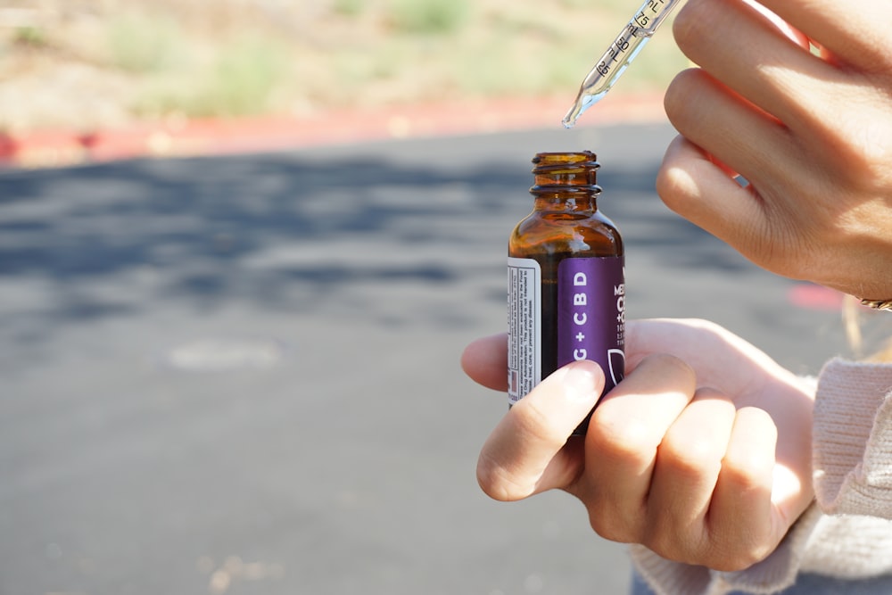 person holding brown glass bottle