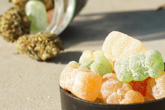 Colorful cannabis-infused gummies displayed in a small glass jar.