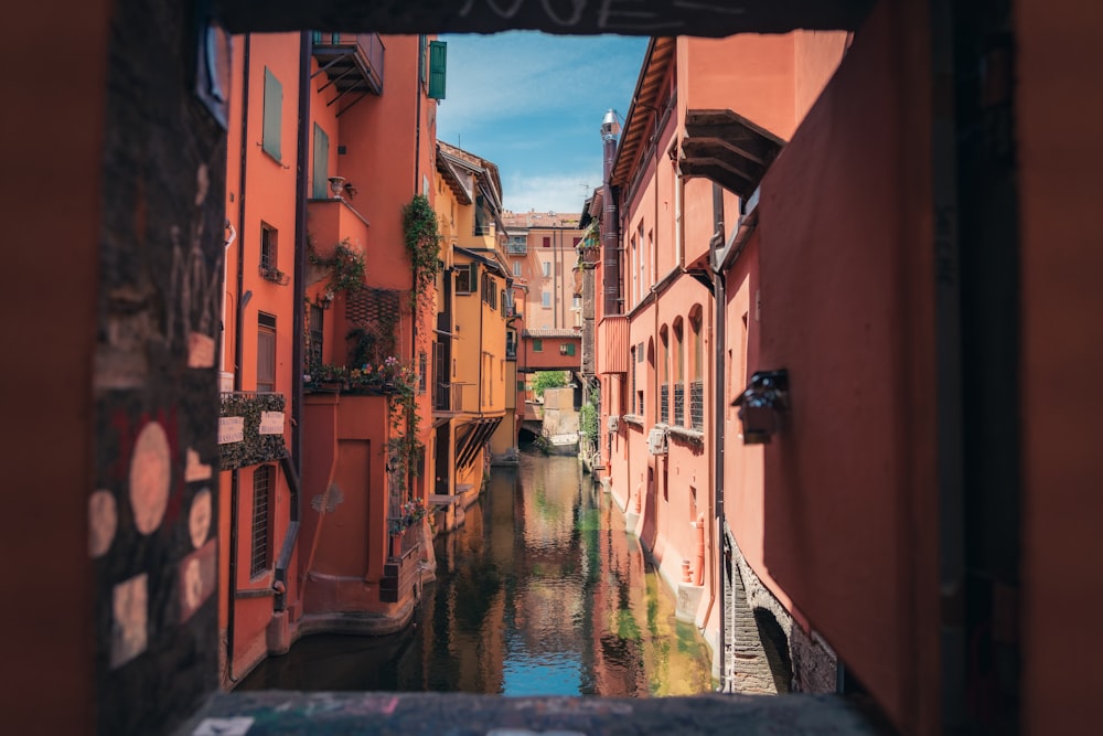 body of water between brown and white concrete buildings during daytime