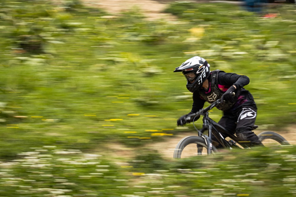 Hombre en chaqueta negra montando en bicicleta en campo de hierba verde durante el día