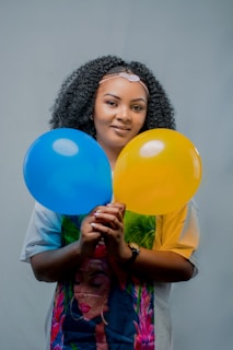 smiling girl holding yellow balloons