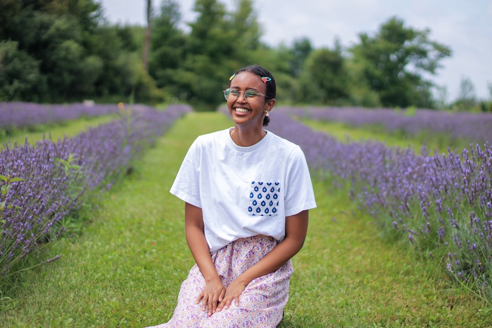 woman in white crew neck t-shirt and blue and white floral skirt sitting on green