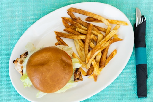 Grilled chicken sandwich served with a side of golden fries on a rustic wooden table.