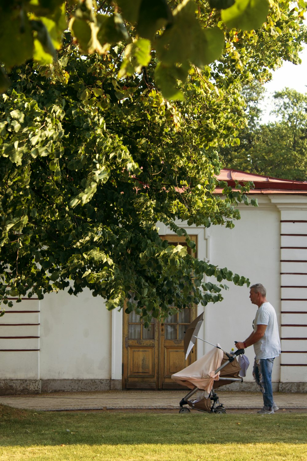 man in white t-shirt and black pants standing beside green tree during daytime