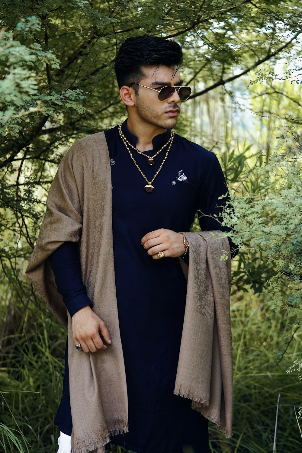 man in black crew neck shirt and gray coat standing near green trees during daytime