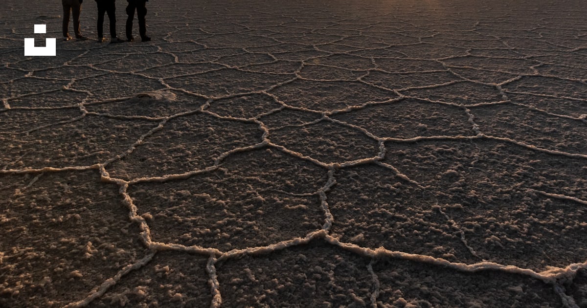 Silhouette de 2 personnes debout sur un sol rocheux pendant le coucher ...