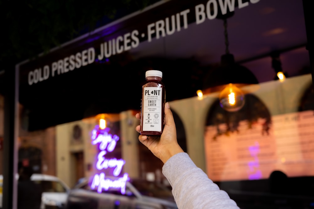 person holding white and black labeled bottle