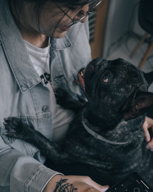 Mujer sosteniendo a su perro mientras se miran con cariño.