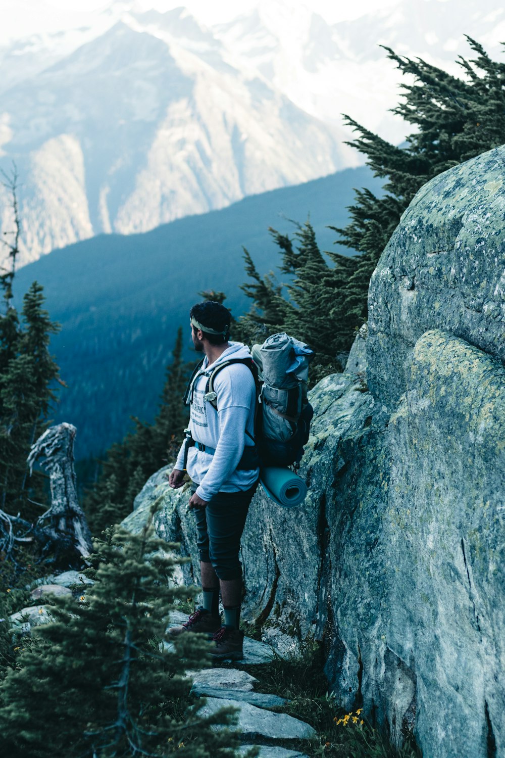 woman in blue jacket and black pants with blue backpack standing on rocky mountain during daytime