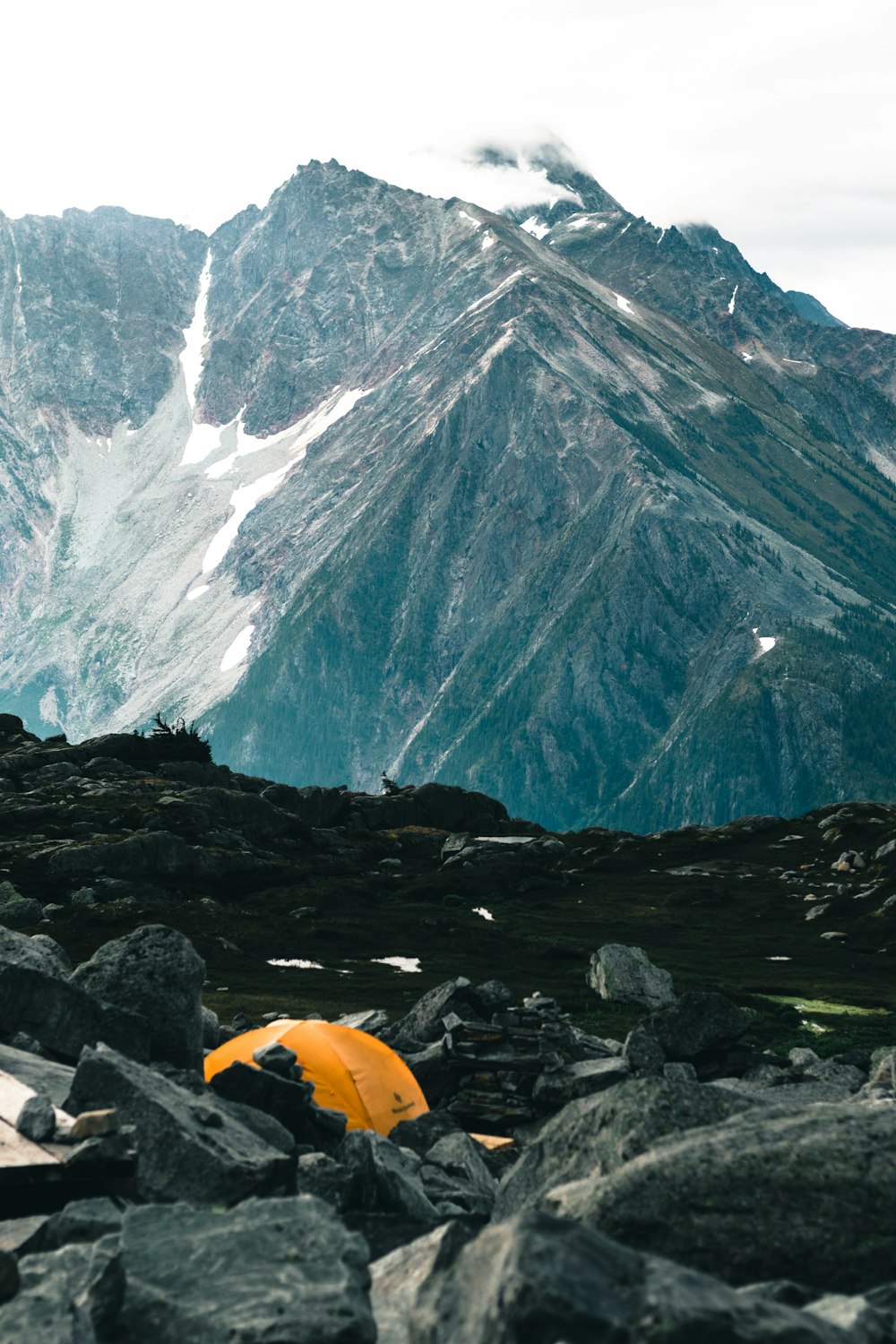 yellow dome tent on rocky ground near mountain