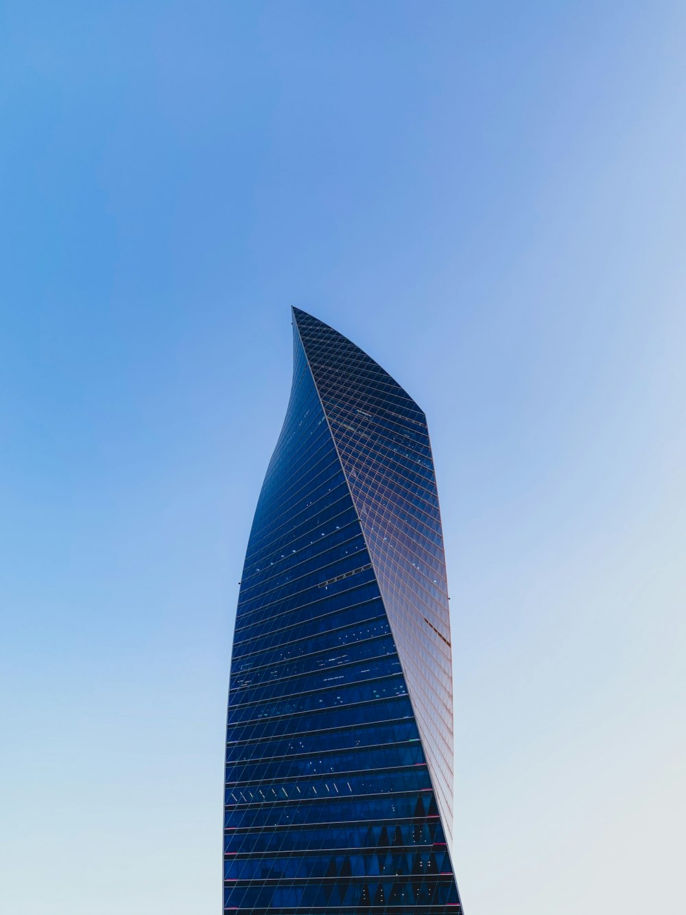 Edificio de gran altura negro y gris bajo el cielo azul durante el día