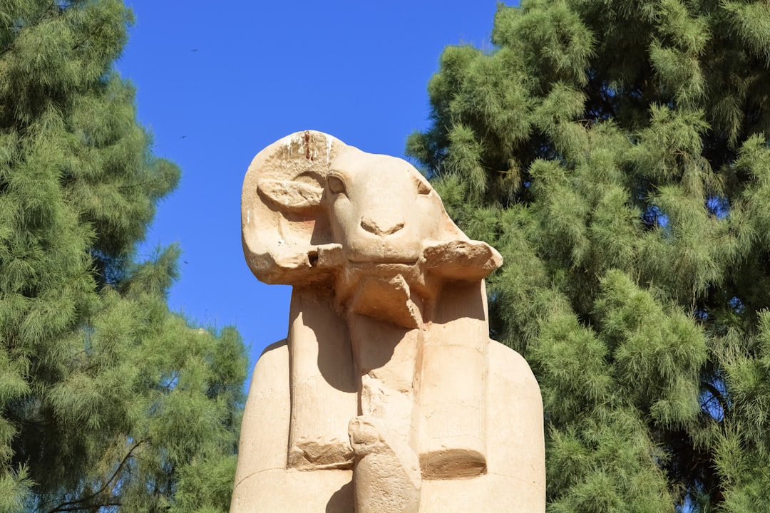 brown concrete statue near green trees during daytime