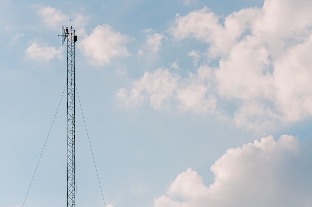 poteau électrique noir sous ciel nuageux pendant la journée