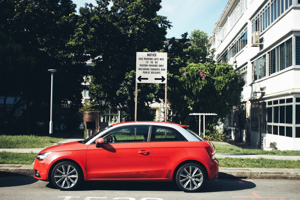 red sedan parked near white building during daytime