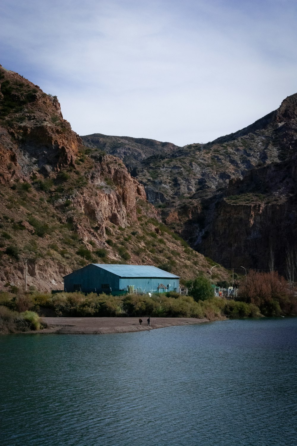 white and blue house near body of water and mountain during daytime