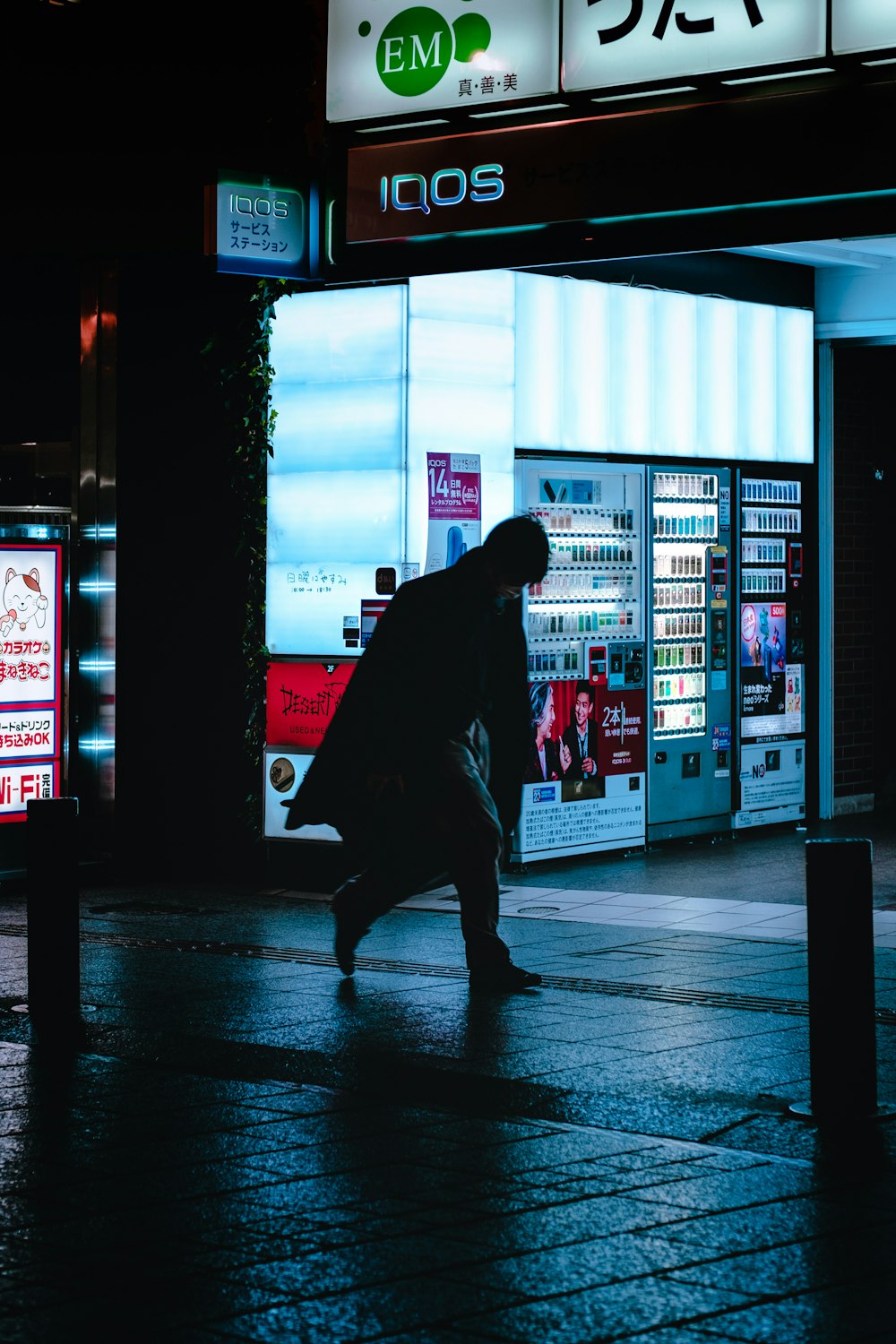 silhouette of man walking on sidewalk during night time