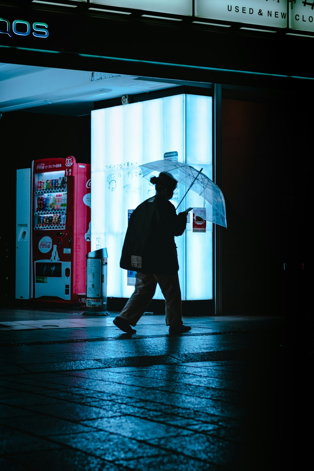 man in black jacket and pants holding umbrella walking on sidewalk