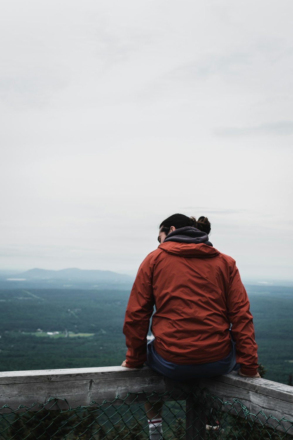 man in orange jacket and black backpack standing on mountain top