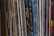 A collection of vinyl records is lined up vertically, with their spines displaying various album and artist names. The records appear tightly packed together, with a mix of modern and classic albums visible. The spines are colorful, indicating a diverse assortment of music genres.