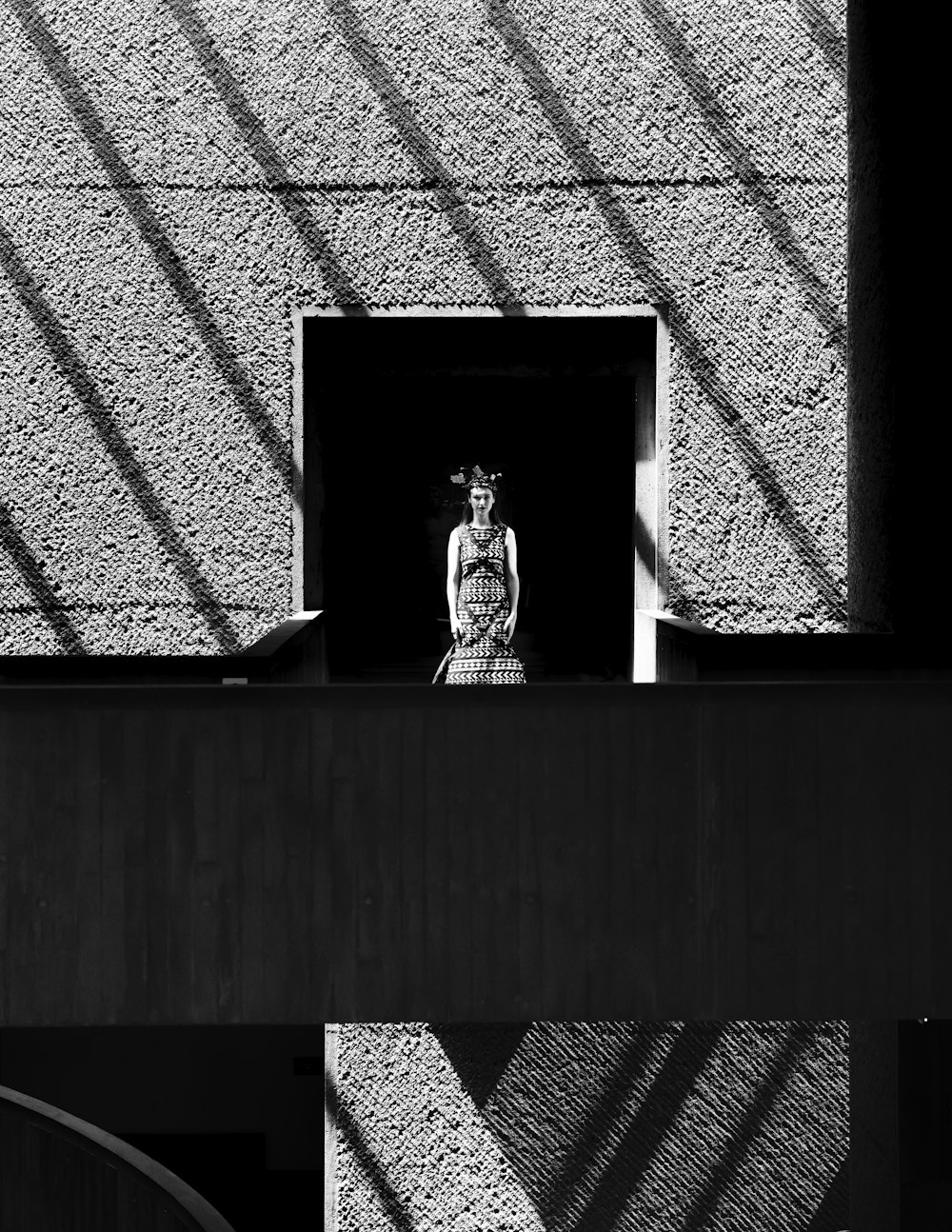 a black and white photo of a woman standing in a window