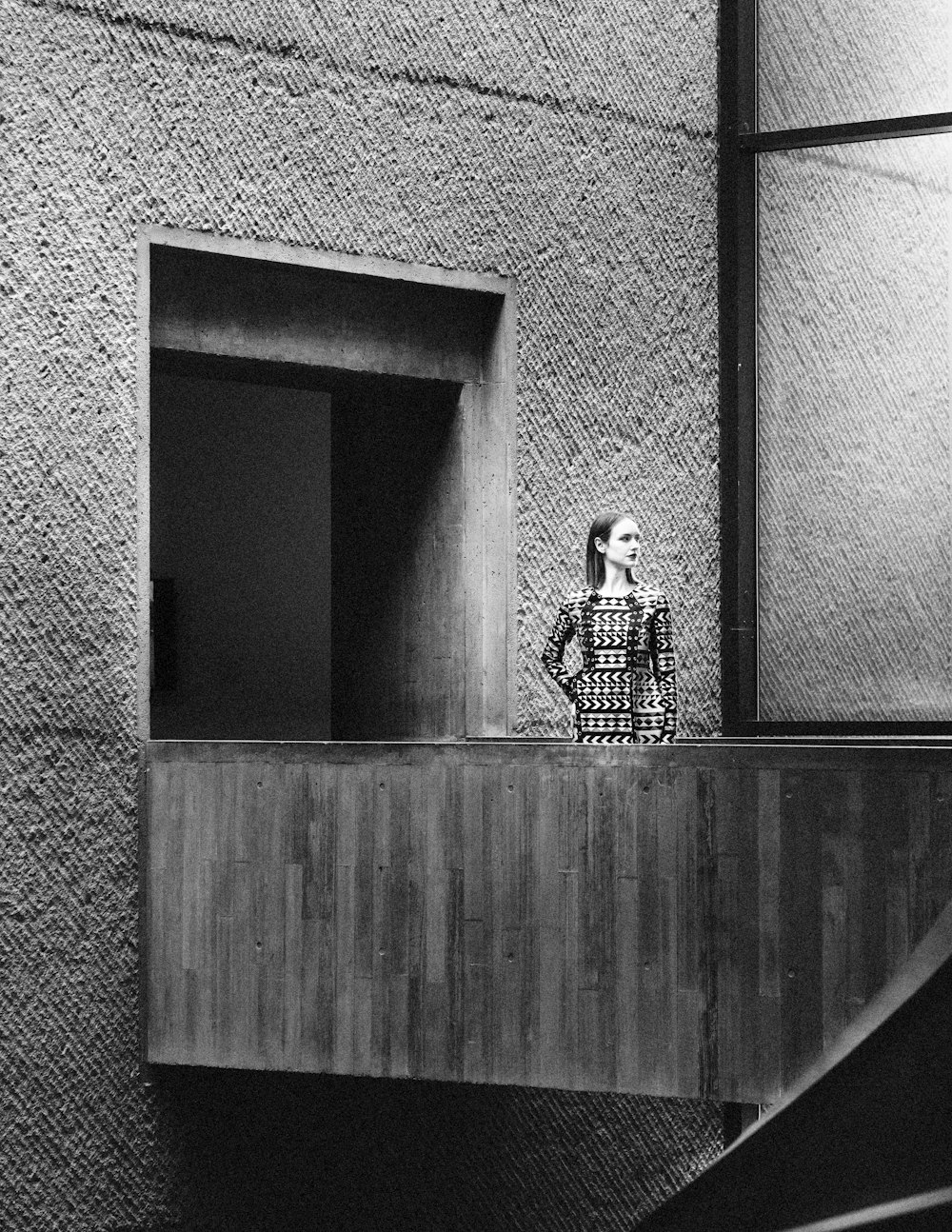 a black and white photo of a woman standing on a balcony