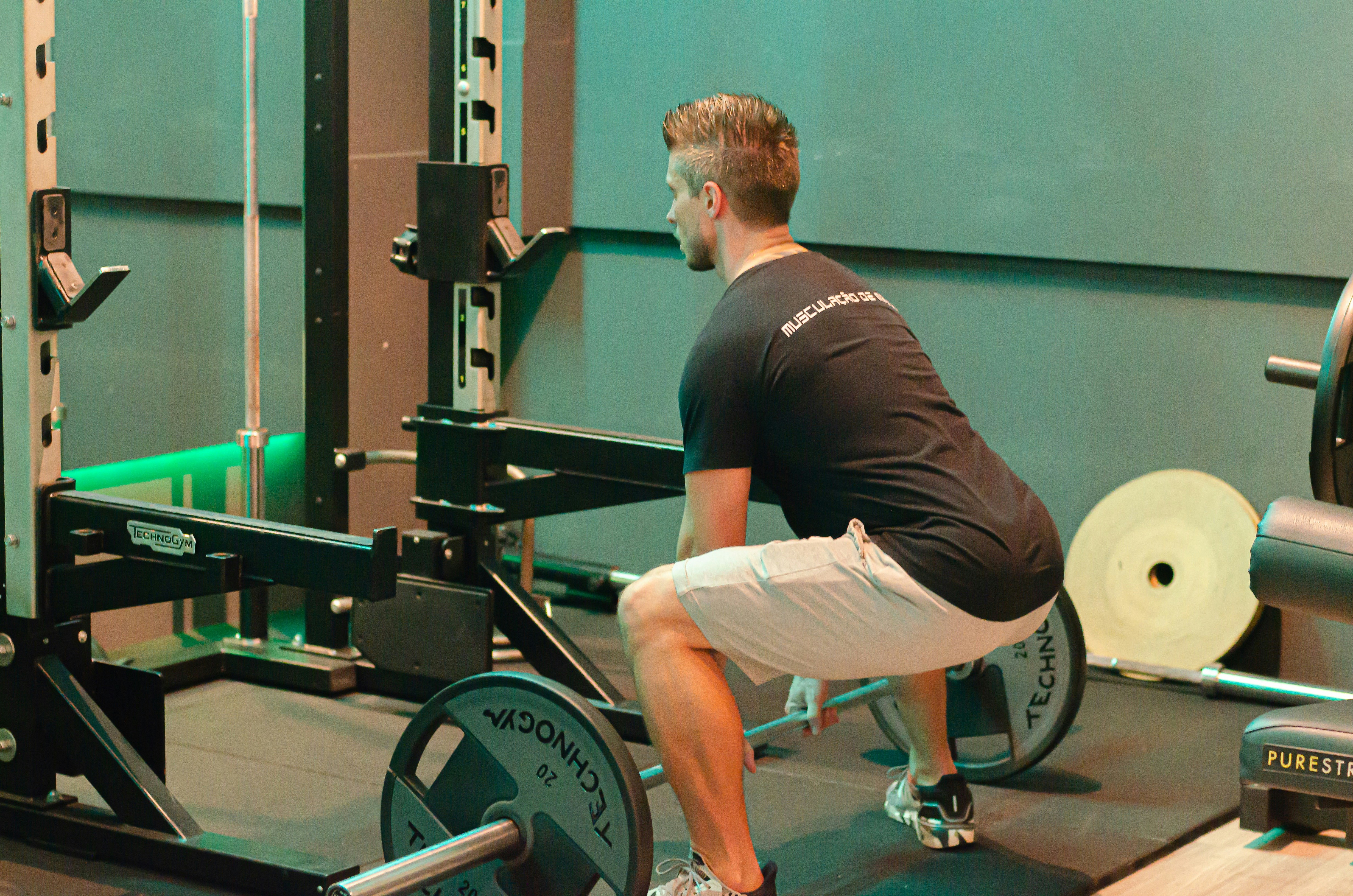 Trainer demonstrating proper squat form to a beginner - boot camp exercises for beginners
