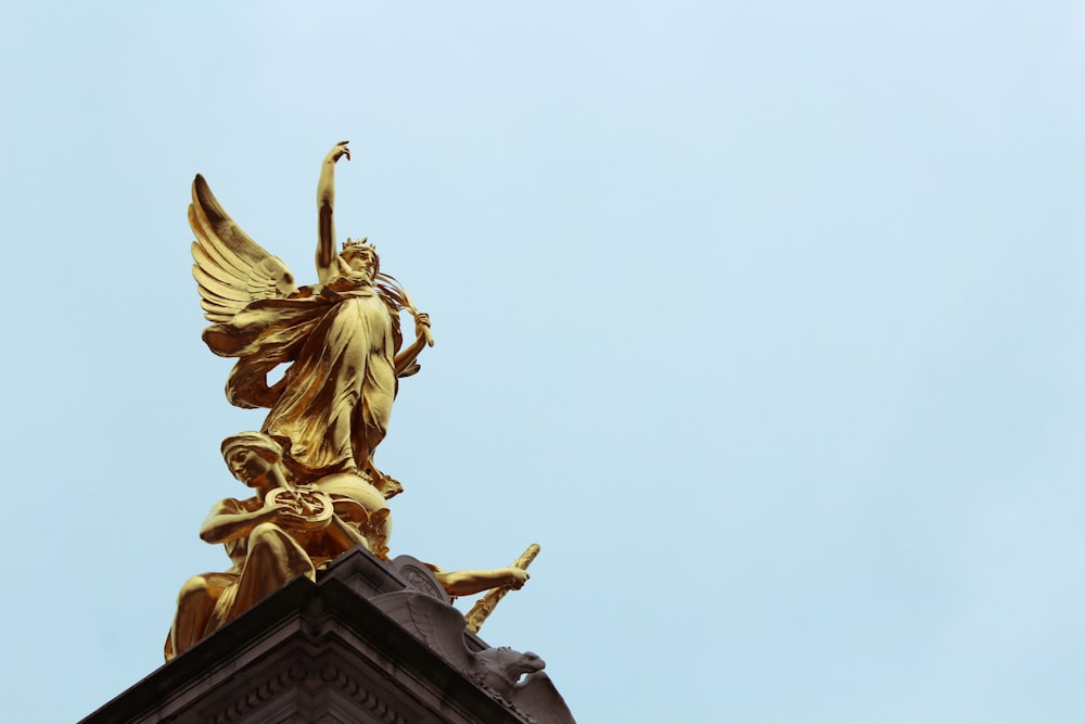 gold angel statue under white sky during daytime