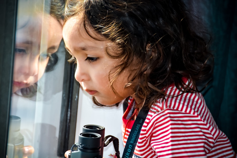 woman in red and white striped shirt holding black dslr camera