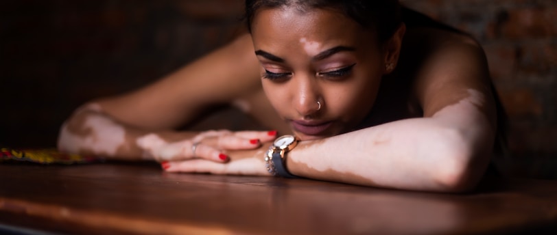 woman in red and white floral dress lying on brown wooden table