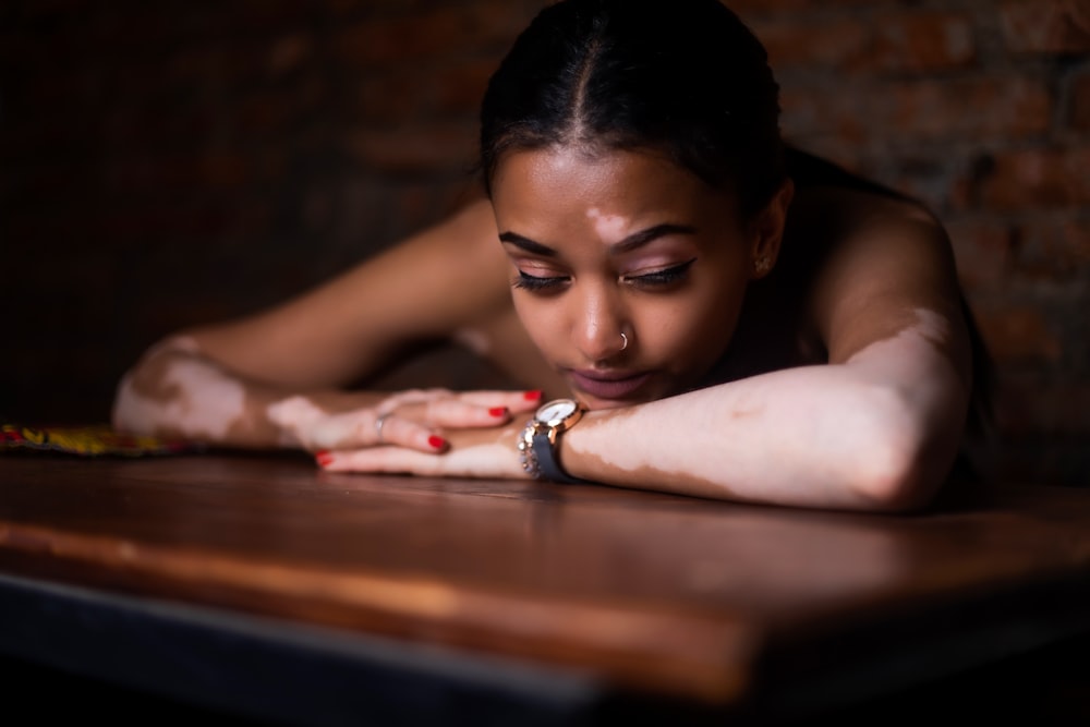 woman in red and white floral dress lying on brown wooden table