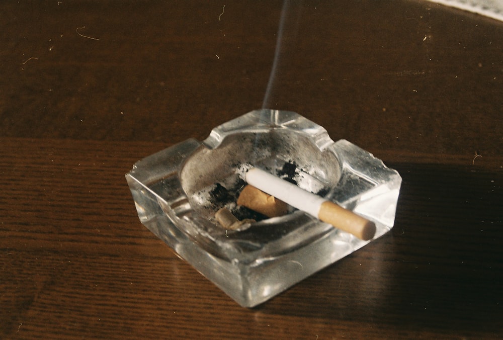 Cigarrillo en cenicero de vidrio transparente