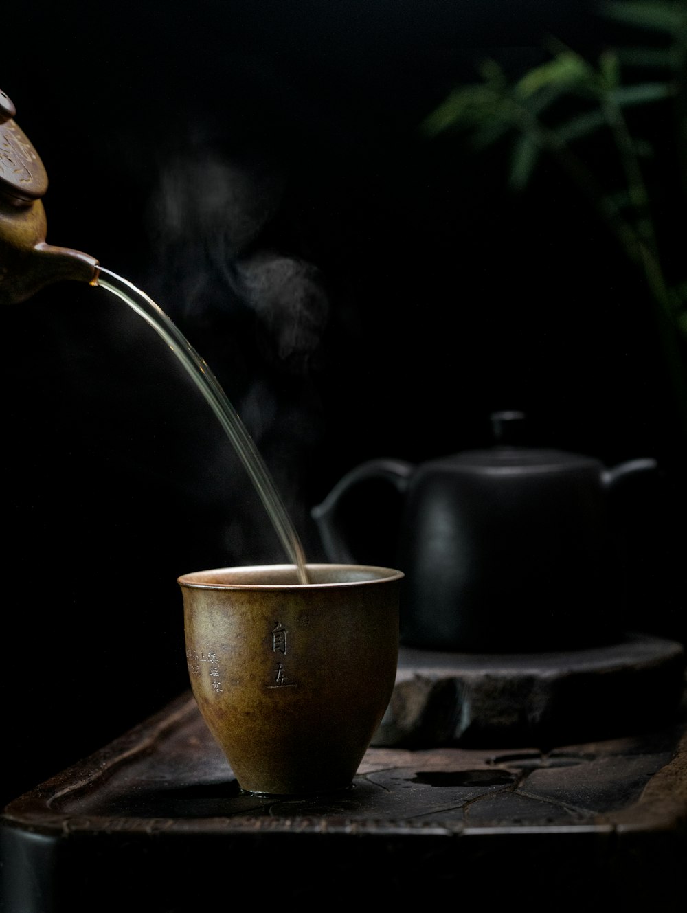 brass kettle pouring water on brown ceramic cup